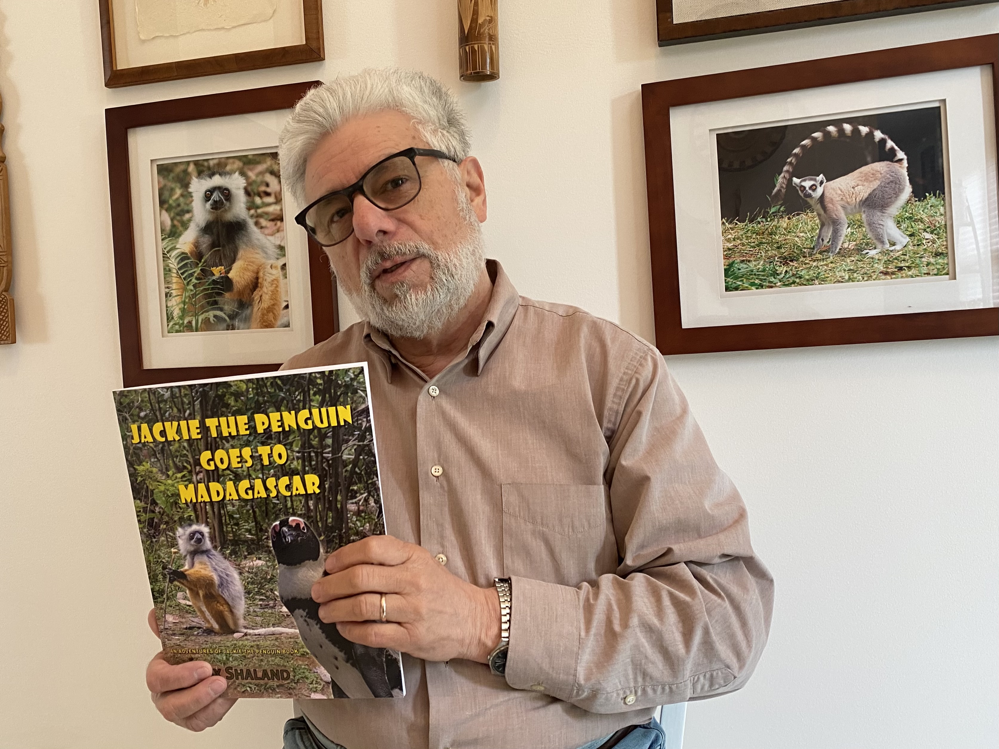 Alex Shaland holds his new book "Jackie the Penguin Goes to Madagascar"